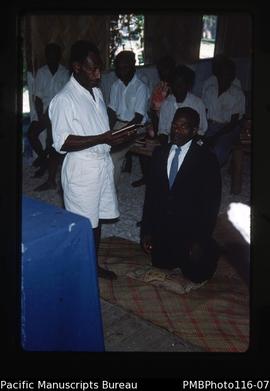 'Pastor Alec kneels during ordination by Pastor Jimmie in Leviamp church'