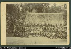 Mounted photograph of a group of Papua New Guinean men and women standing and seated in front of ...