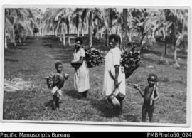 Two ni-Vanuatu women and two children carrying wood and coconut