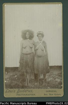 Mounted photograph of two Papua New Guinean women standing in front of a wall.