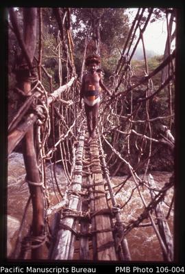 [Beni Wenda (our guide) crossing a traditional hanging bridge of vines and wood plants over the B...