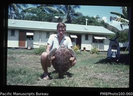 "Tim Bayliss-Smith VSO with green turtle from Honiara market, outside government housing in ...