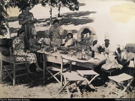Women and children at table wearing party hats, probably Wintua mission station, South West Bay, ...