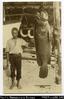 Postcard of Solomon Islands man standing beside a large fish hung up for display.