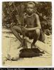 Young Solomon Islands boy holding bow and arrows with dead bird on ground in front of him. Writte...