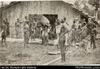 Santa Cruz men and boys standing by store shed (postcard). Written on front in red: 'Natives, Gra...