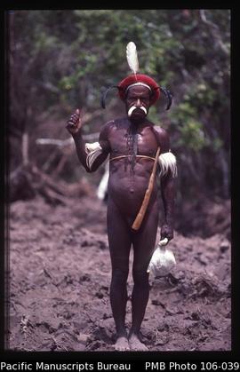 [Dani man just off road north of Wamena town; white feathers and locally made red cap. Same man a...
