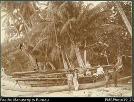 Large outrigger canoe on beach, with three Papua New Guineans and five Europeans.