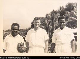 Two ni-Vanuatu and one European men, standing outside. One holding a bible.