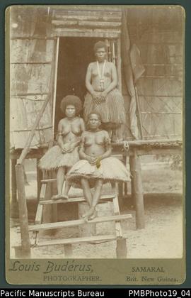 Mounted photograph of three Papua New Guinean women standing and sitting on the steps of a dwelling.