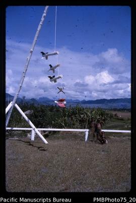 Mt Hagen [a “mobile”? hanging from a pole, three children by white fence, Western Highlands Distr...