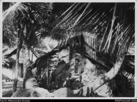 Young man sitting in front of dwelling, probably south west Malekula