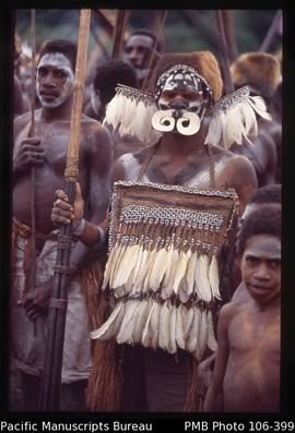 [Asmat man with  large bark-string bay decorated with cockatoo feathers; clamshell nose piece, cu...