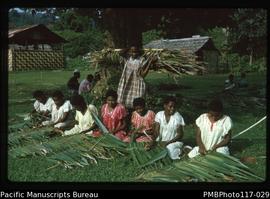 ‘Letia teaches girls. District School girls make thatch for dining room, South West Bay’