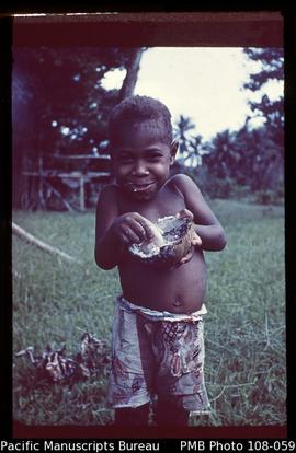 [Smiling child eating coconut]