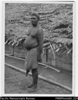 ni-Vanuatu man standing by a low thatched house