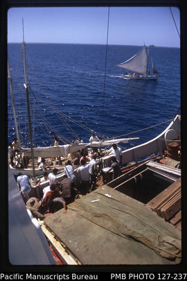 'Working cargo between MV Olovaha and sailing cutter, with second cutter in background, Tonga'