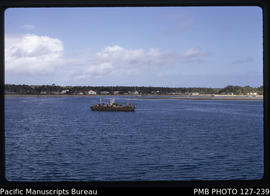 'MV Fangailifuka and steel barge waiting for MV Olovaha, with Pangai seen in background, Tonga'