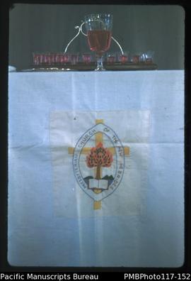 ‘Communion set on table and N.H. [New Hebrides] crest on cloth, Wintua Church’