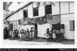 Samarai [Island, Milne Bay District;  building displaying Australian flag and two flags of the Un...