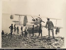 Airplane in ocean with men gathered around, Malekula