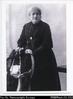 Photograph of an elderly lady standing behind a chair
