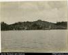 Larger format photograph of European settlement (two buildings on hilltop) taken from sea/ship. T...