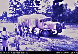 'Highlands Highway: heavily-loaded yellow Oshkosh just arrived in Mount Hagen from Lae'