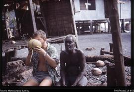 'John Baker drinking a green coconut, with Nngu, Assistant District Headman, Vori, Ranonnga Island'