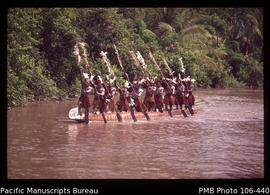 Men paddling dugout War canoe, Asmat