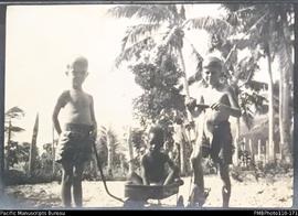 'D.R and Ambongmen.' Donovan and Roger Stallan with Ambongmen in toy wagon, probably at Wintua mi...