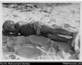 Young boy (possibly Leloch) lying on sand at Aulua Malekula