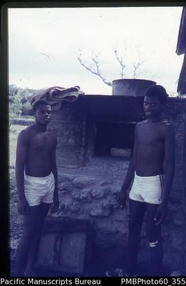 Two ni-Vanuatu young boys standing by an oven
