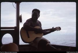 'Dominic Otuana playing guitar on board boat returning to Honiara from Auki'